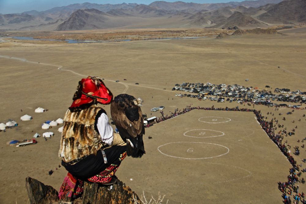 A man with an eagle sitting on a high place