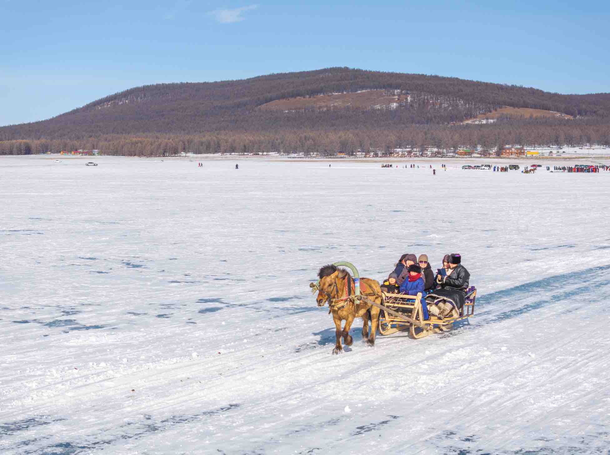 A stunning image of Mongolia in winter showcasing a group of people enjoying winter activities such as skiing and snowboarding.